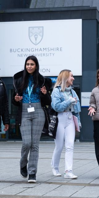 Four female students walking in front of the Gateway building