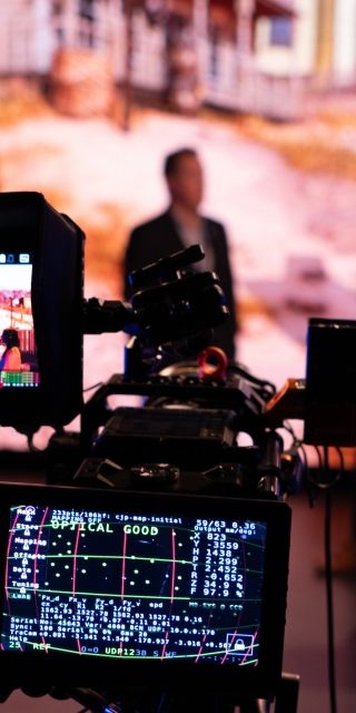 Four people talking in front of an LED Screen, cameras pointing at them