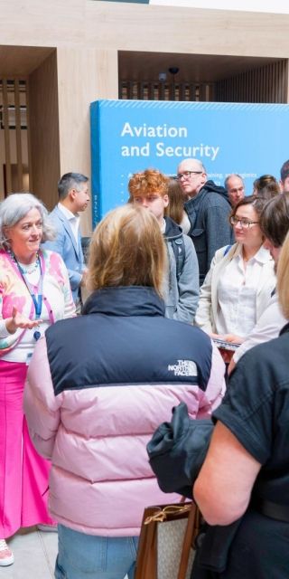 A group of students and parents stood in a cricle listening to a lecturer give a talk about a subject at an Open Day.