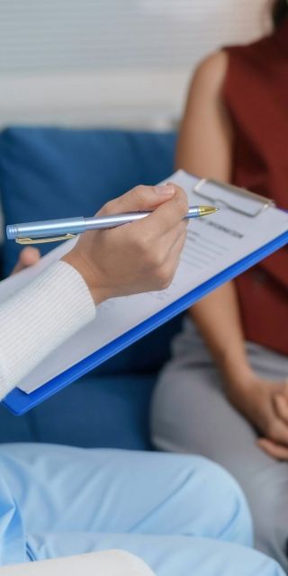 doctor taking notes while talking to patient