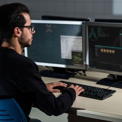 Man with glasses using linux software on computer at desk