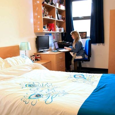 A student sitting at their desk in a standard en suite 