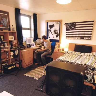 BNU student in Hughenden accommodation studio bedroom sitting at desk with musical equipment around
