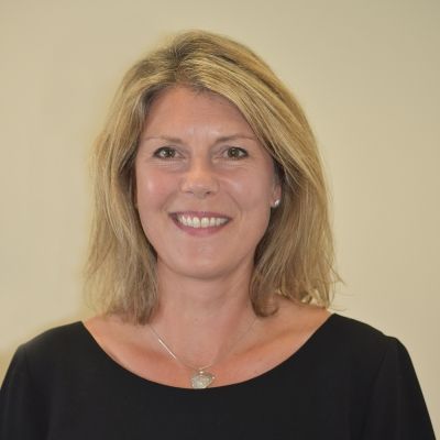 A head and shoulders shot of Anne Followell wearing a black top looking directly into the camera stood face on