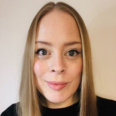 Head shot of a smiling Annette Palmer stood face on looking directly into the camera stood in front of a white wall