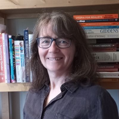 Head and shoulders photo of a smiling Elaine Welsh stood in front of a book case