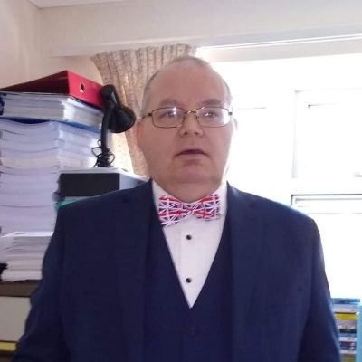 A head and shoulders shot of a smiling Paul McCreary stood in an office wearing a three piece suit with a union jack bow tie