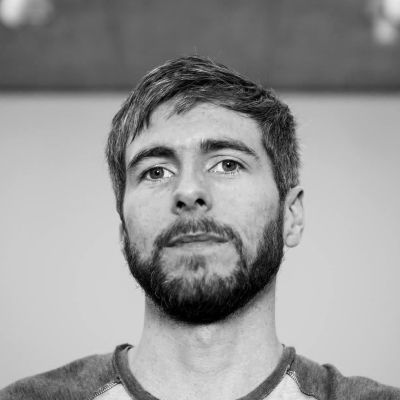 Head and shoulders shot of a smiling Gerard Gormley stood face on looking directly into the camera