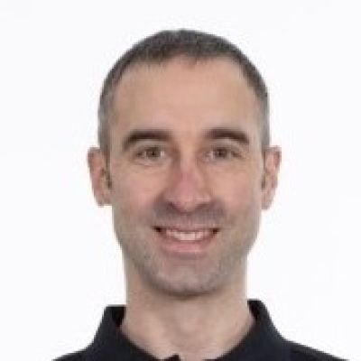 Head and shoulders shot of a smiling Kevin Campbell-Karn wearing a black polo top looking straight into the camera