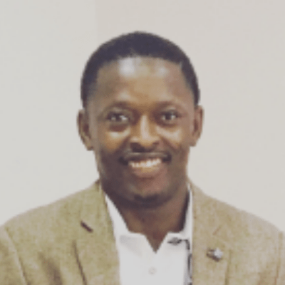 Head and shoulders shot of Emmanuel Unuafe, an academic at BNU, wearing a white shirt and stone coloured jacket