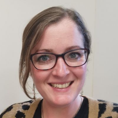 Headshot of a smiling Claire Stringer wearing glasses and looking directly into the camera
