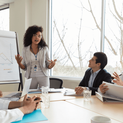 Business meeting amongst five members of staff sat around a table
