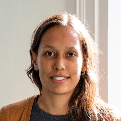 A head shot of a smiling Mona Camille stood facing directly into the camera