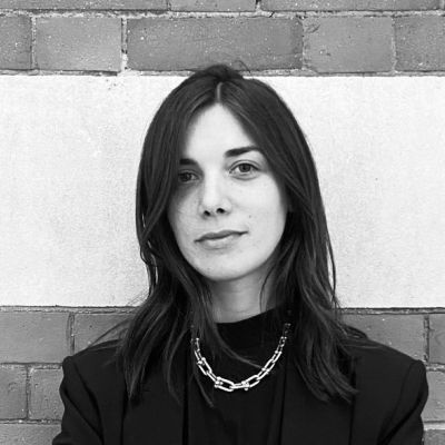 A black and white photo of a smiling Michela Falcone stood facing towards the camera