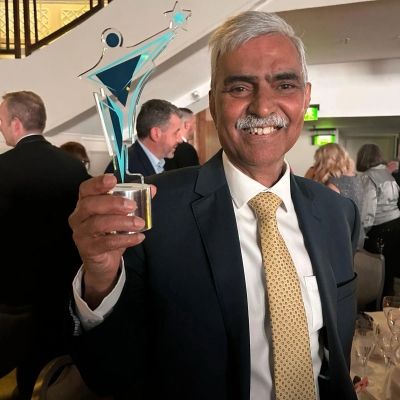 Mike holds his award and smiles