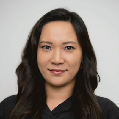 A head and shoulders shot of a smiling Ravina Eunhye Huh standing in front of trees looking directly into the camera