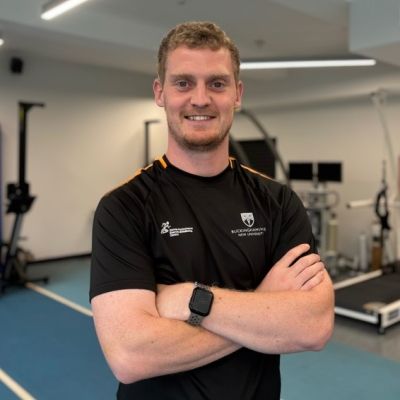 Man smiling with his arms crossed in a sports room.