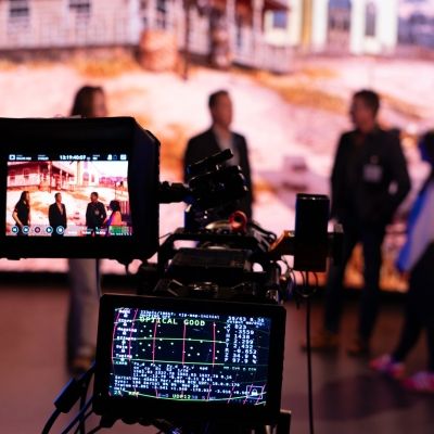 Four people talking in front of an LED Screen, cameras pointing at them