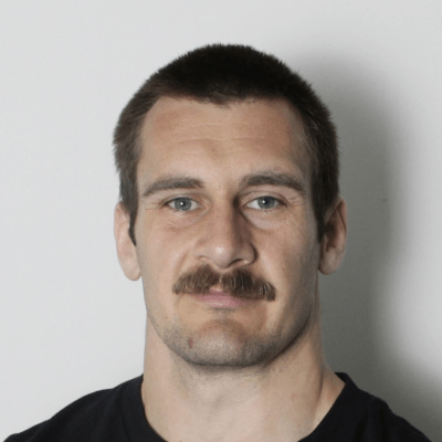 Headshot of Henry Brewster against a grey background.