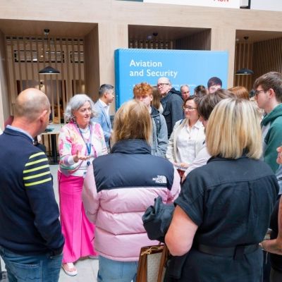 A group of students and parents stood in a cricle listening to a lecturer give a talk about a subject at an Open Day.