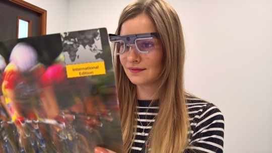 Female student wearing eye tracker while reading a magazine