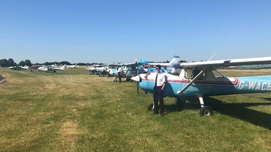Planes lined up on an airfield on a sunny day