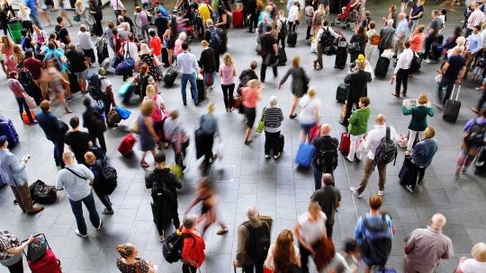 People at airport with luggage walking round and looking up 
