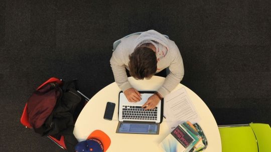 Aerial shot of a student sat at a round table on their laptop