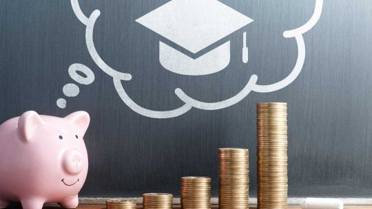 Piggy bank and money on table with graduation hat in background