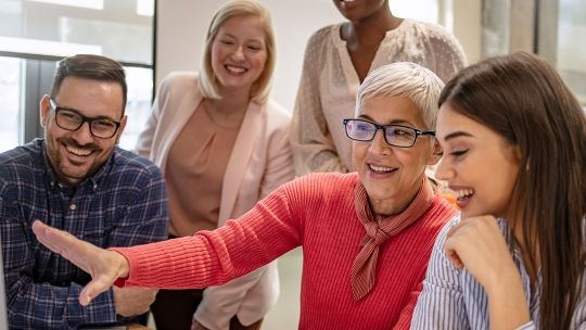 Five people all smiling and in mid conversation 