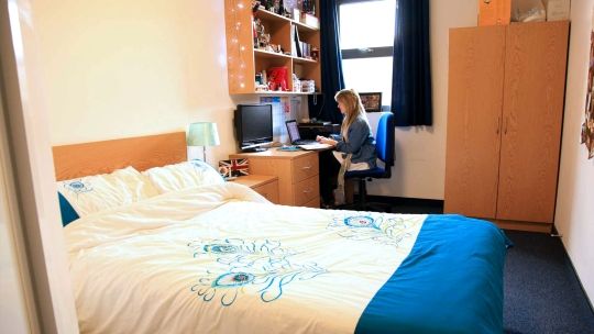 A student sitting at their desk in a standard en suite 