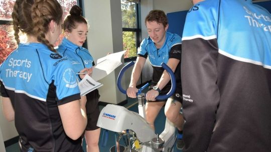 Sports therapy students working together on bike
