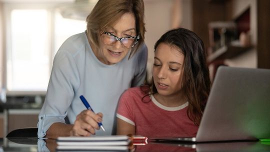 Parent helping her child with work at a desk and laptop