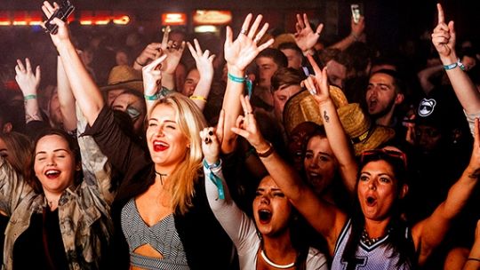 BNU students in a nightclub with their hands in the air and shouting looking towards the stage