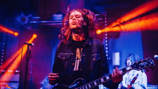 A guitarist playing under strobe lighting in a concert at an event organised by Bucks Students' Union
