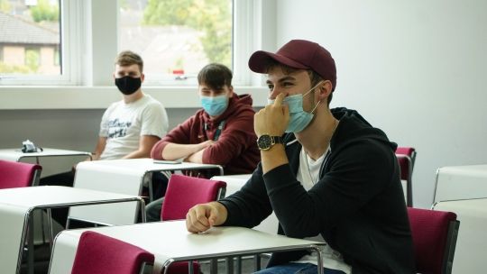 Three male students wearing face coverings in the classroom