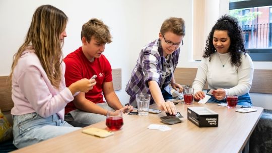 Four students playing cards at the communal area in Hughenden accommodation