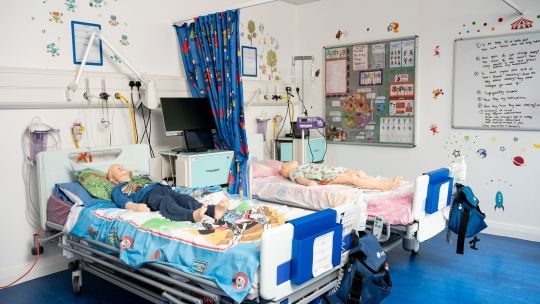 Two hospital beds in a simulation room with dummy children laying on them