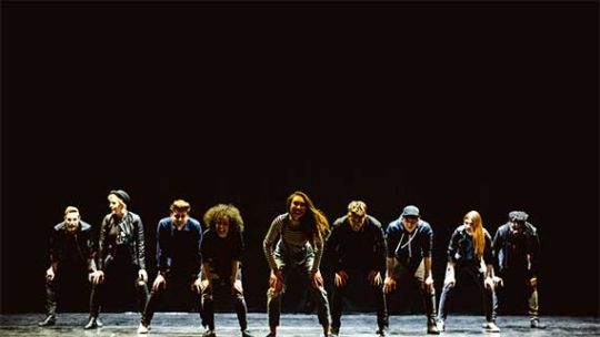 Musical Theatre students performing a dancing routine on stage under the spotlight
