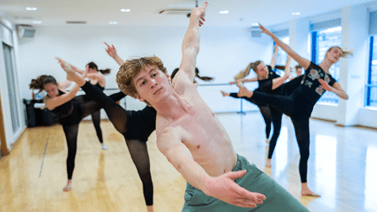A dance student leading fellow dance students in a choreograph in the dance studios