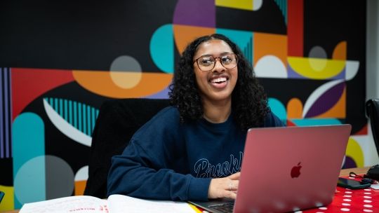 Creative Advertising student at laptop smiling