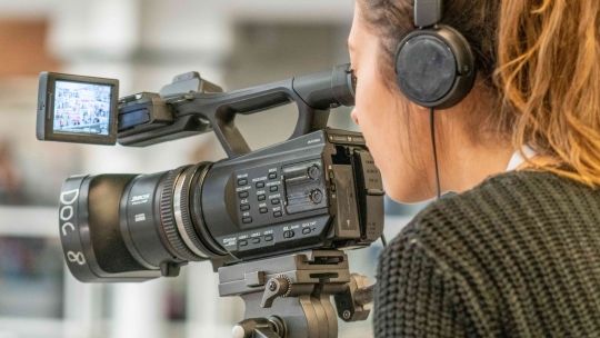 woman operating a camera with black headphones