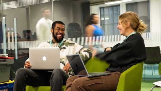 Two students with laptops in a classroom