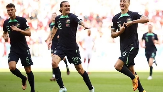 three footballers mid-run on pitch