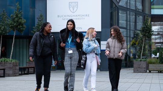 Four female students walking in front of the Gateway building