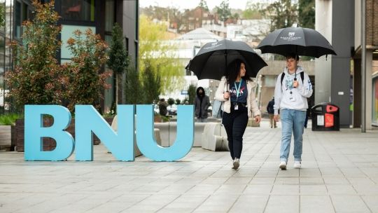 Two students walk on BNU concourse 