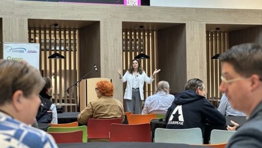 Laura Smith stands at podium and speaks to delegates with hands raised