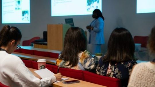 The back of three people's heads sat in a lecture theatre facing a guest speaker.