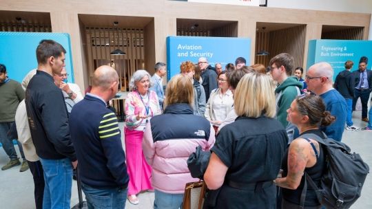 A group of students and parents stood in a cricle listening to a lecturer give a talk about a subject at an Open Day.