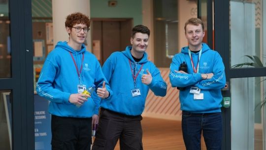 Three student ambassadors smiling and giving thumbs up at an open day